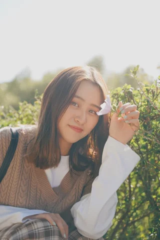 小花遮住一眼，微笑與抬手讓人物和植物產生輕巧互動